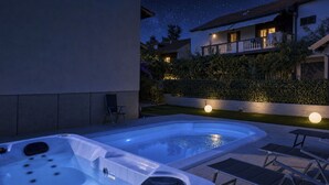 Een bubbelbad met bedieningspaneel, een lounge stoel en een tafel.