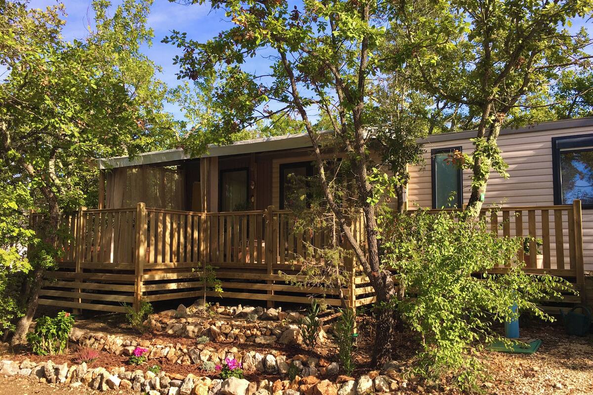A wooden cabin with a porch, surrounded by a garden with rocks and plants.
