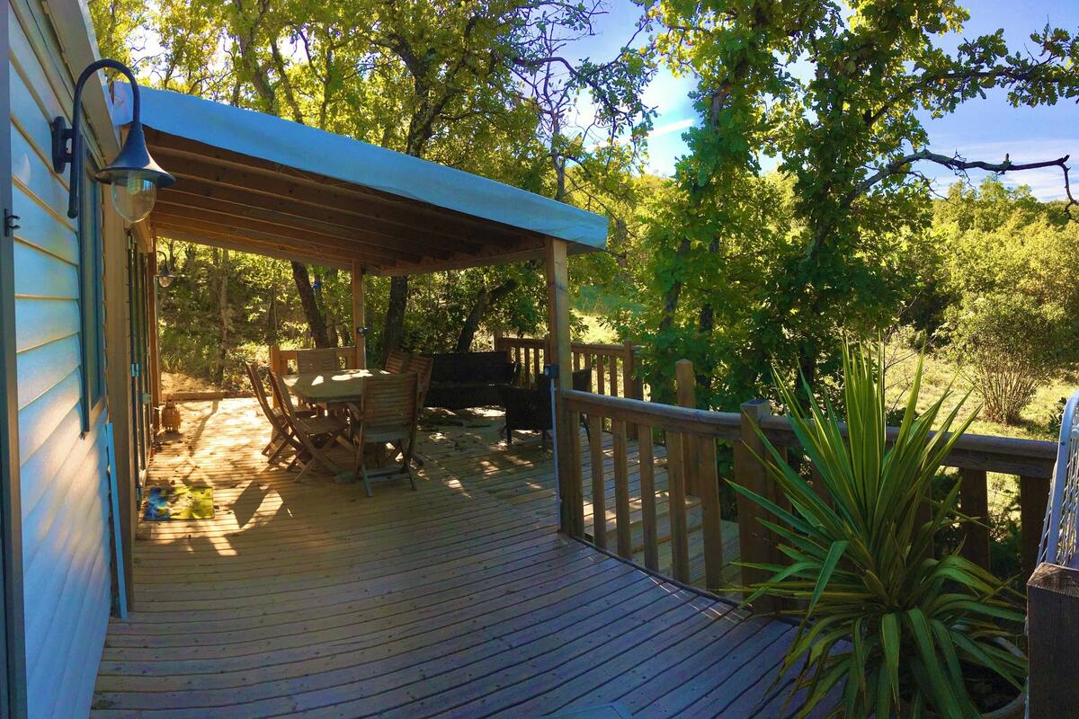 A wooden deck with a covered area, a dining table, and chairs.