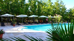 A pool area with lounge chairs and umbrellas, surrounded by trees and potted plants. - Domaine le Clos des Capitelles (Saint-Privat-de-Champclos)