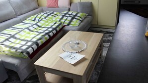 A small, neatly arranged room with a sofa, a wooden table, and a glass on the table.
