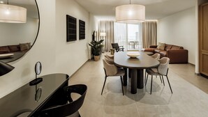 Un salon moderne avec un coin repas, comprenant une table ronde, des chaises, un canapé et un grand miroir.