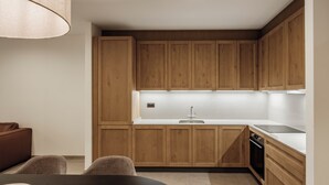 Une cuisine moderne avec des meubles en bois, un plan de travail blanc et un coin repas comprenant une table et des chaises.