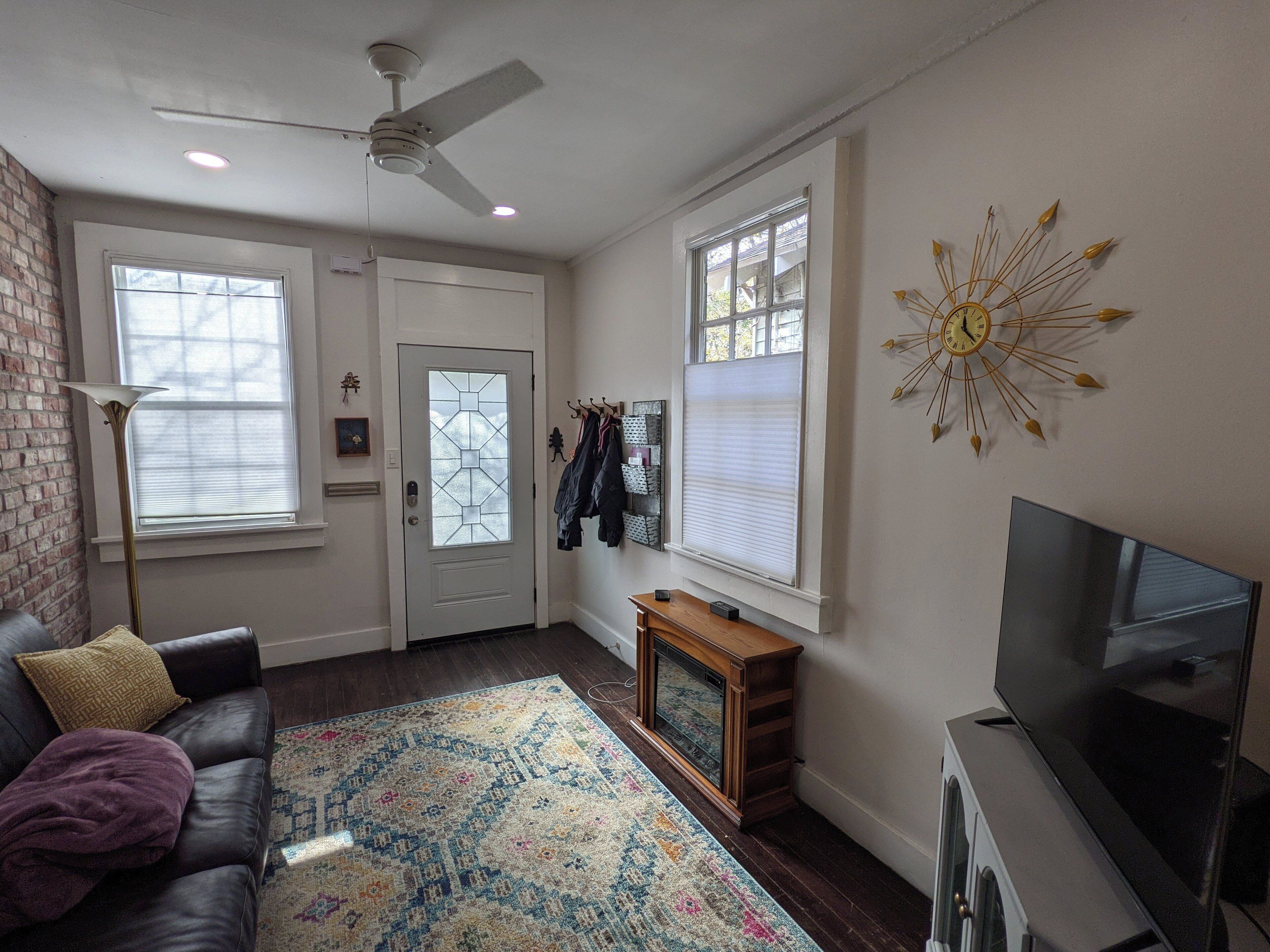 A living room with a leather couch, a television, a fireplace, and a large window.