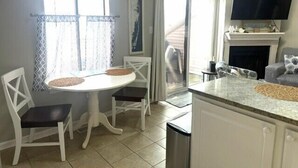 A kitchen with a dining table, chairs, a TV, and a fireplace. - New for 2025! Beached Themed Two Bedroom Direct Bayfront on 32nd Street (Ocean City)