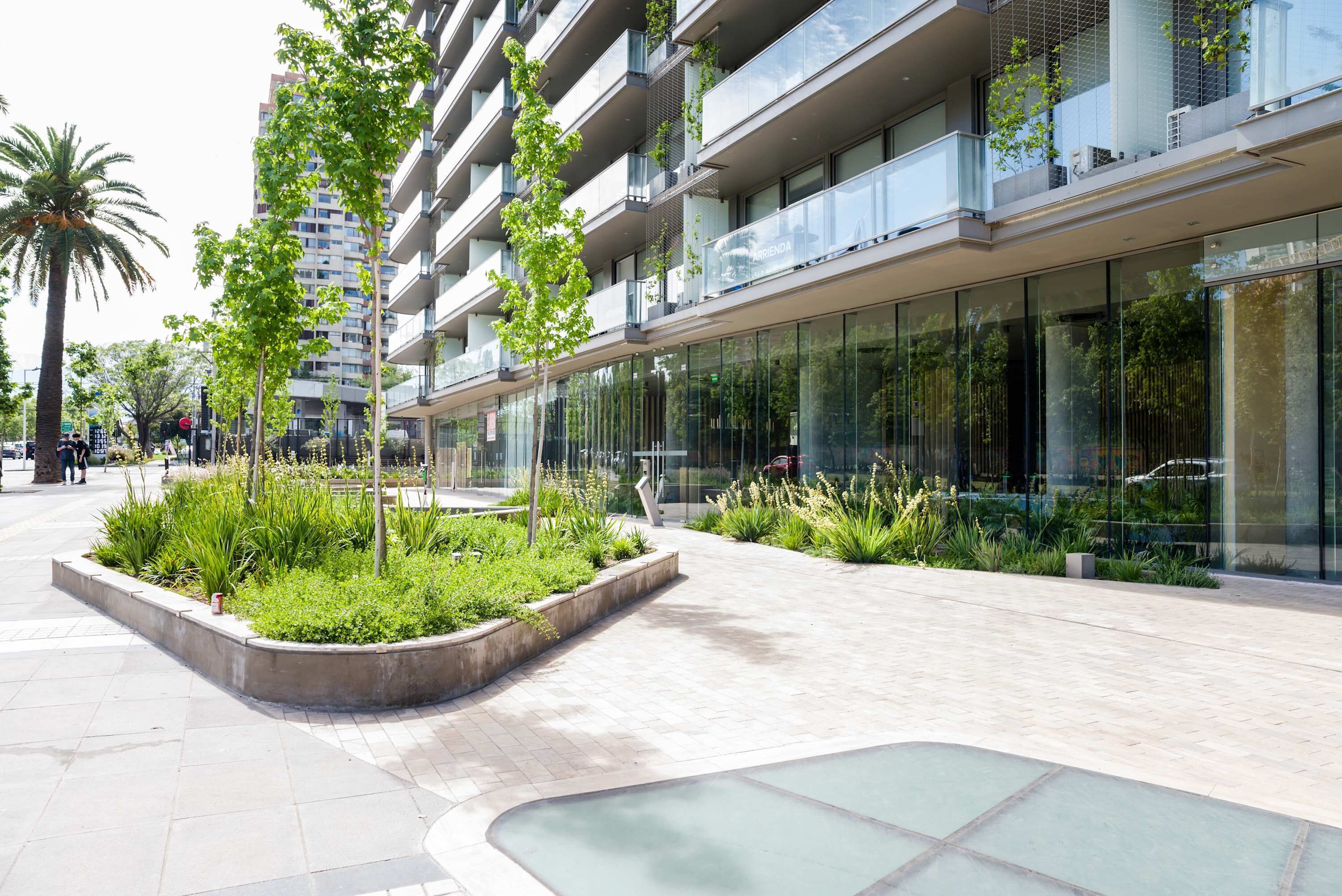 A modern building with a glass facade, a landscaped area with plants, and a curved glass feature.
