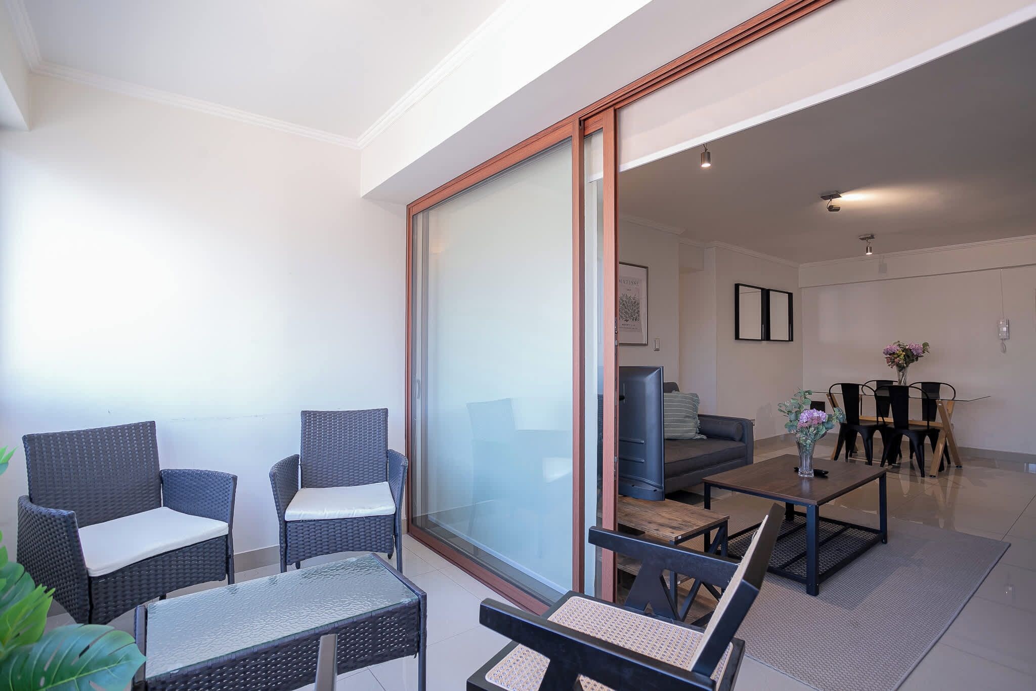 A modern living room with a sofa, two armchairs, a coffee table, and a dining area with chairs and a table.