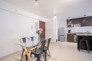 A modern kitchen with dark cabinets, a microwave, and a refrigerator. - Spacious 2BR/2BA Apt. in the Heart of Las Condes (Las Condes)