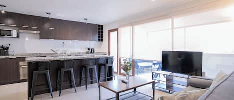 A modern kitchen with dark wood cabinets, a granite countertop, and a built-in microwave.