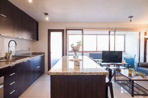 A modern kitchen with dark cabinetry, a granite countertop, and a central island with a vase of flowers.