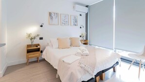 A modern bedroom with a bed, bedside tables, a chair, and artwork on the wall. - Modern 2BR Suite | Prime Las Condes Urban Living (Las Condes)