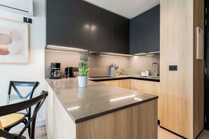 A modern kitchen with a central island, dark cabinets, and a coffee maker.