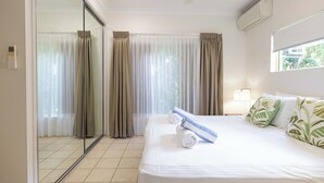 A hotel room with a large bed, a sliding glass door, and a window with curtains.
