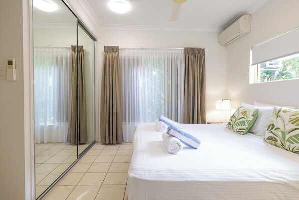 Una habitación de hotel con una cama grande, una puerta corrediza de vidrio y una ventana con cortinas.