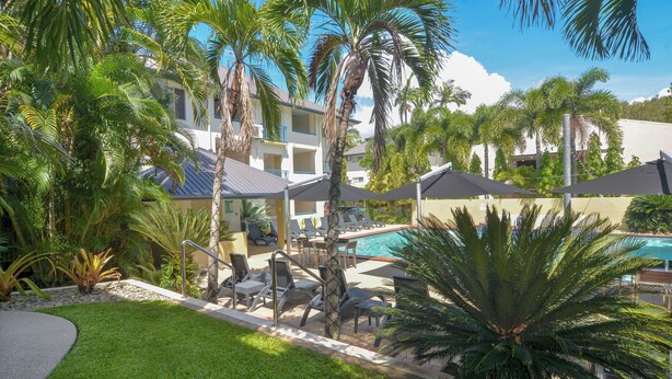 A resort with a swimming pool, palm trees, and lounge chairs.