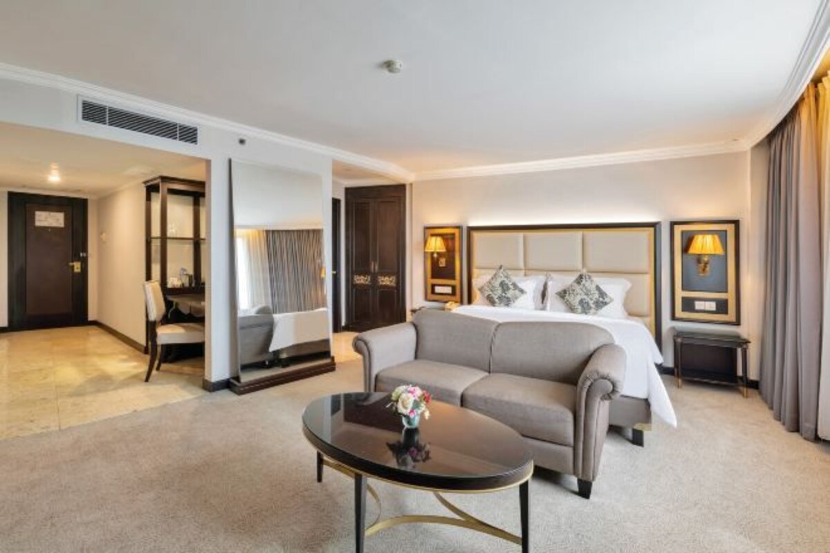 Een hotelkamer met een bed, een slaapbank, een salontafel en een nachtkastje met een lamp.