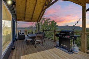 Una terrazza coperta con barbecue e zona salotto, affacciata su un panorama suggestivo.