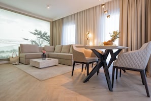 Una sala de estar moderna con un ventanal grande, un sofá, una mesa de centro y una mesa de comedor con sillas.