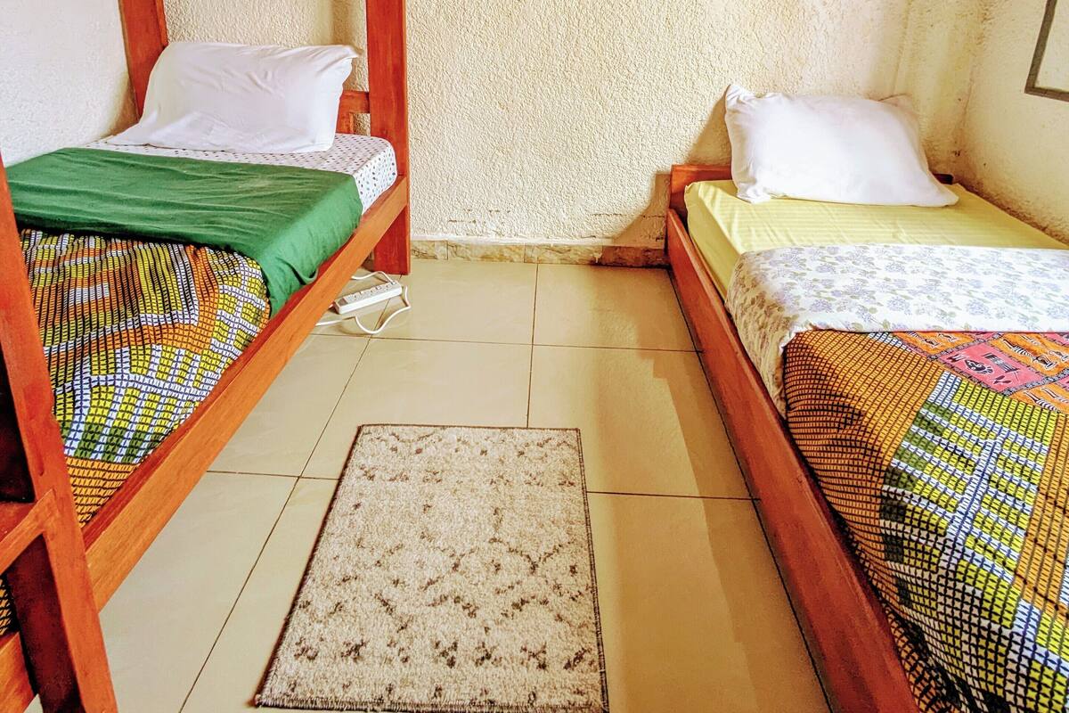A small, cozy room with two bunk beds, a patterned rug, and a plain wall.