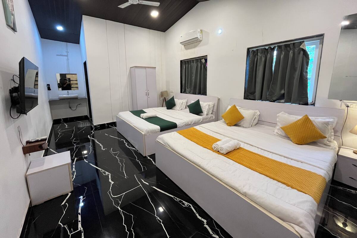 Habitación de hotel con dos camas, un espejo, televisión y baño.