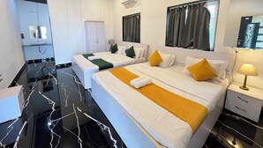 Habitación de hotel con dos camas, un tocador con espejo, un armario y un baño con lavamanos y espejo.