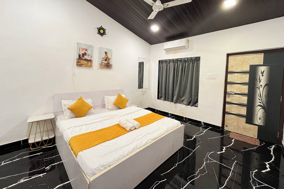 Un dormitorio moderno con cama, ventilador de techo, obra de arte en la pared y ventana con cortinas.