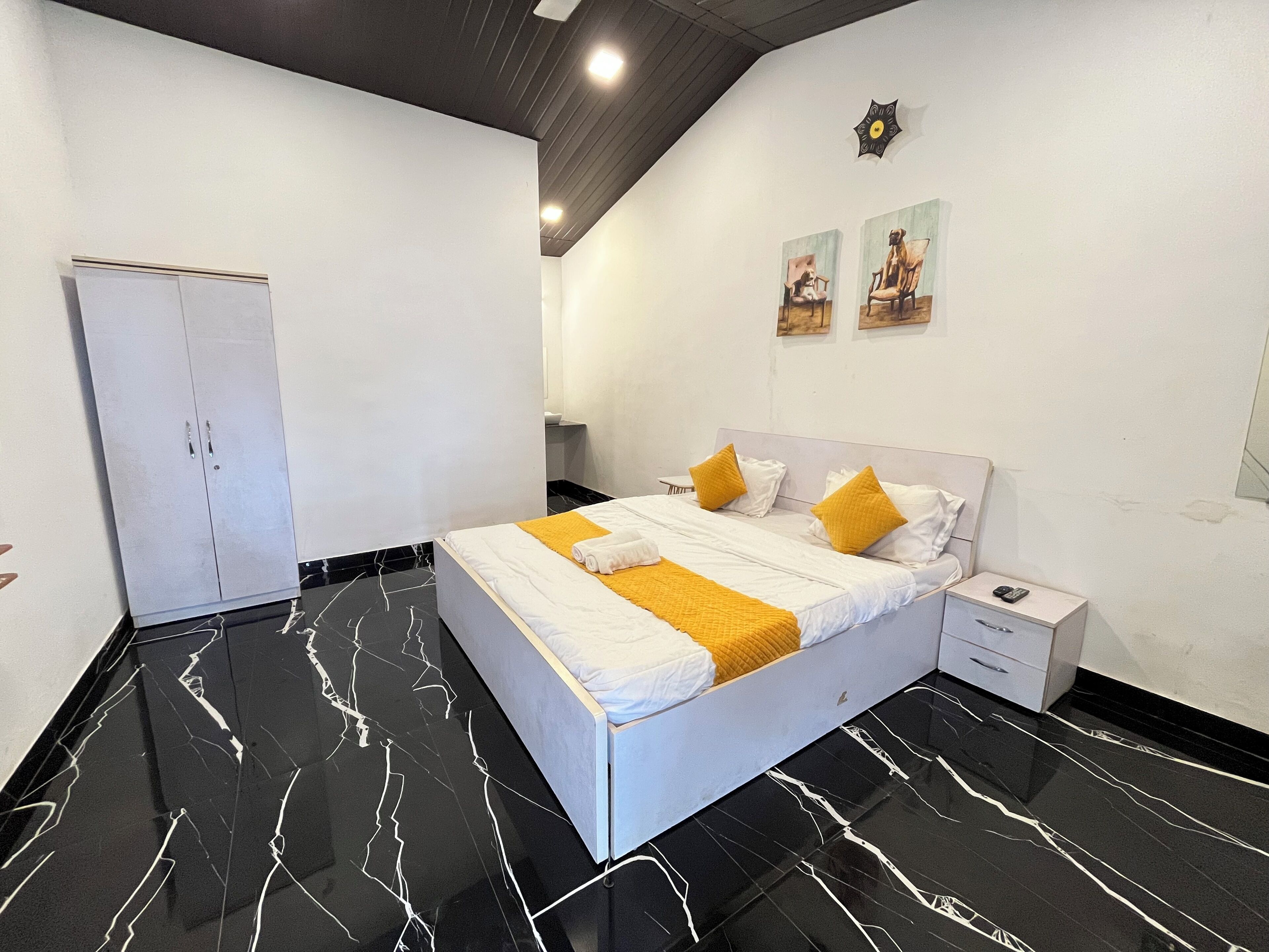 A modern bedroom with a bed, nightstand, wardrobe, and artwork on the wall.