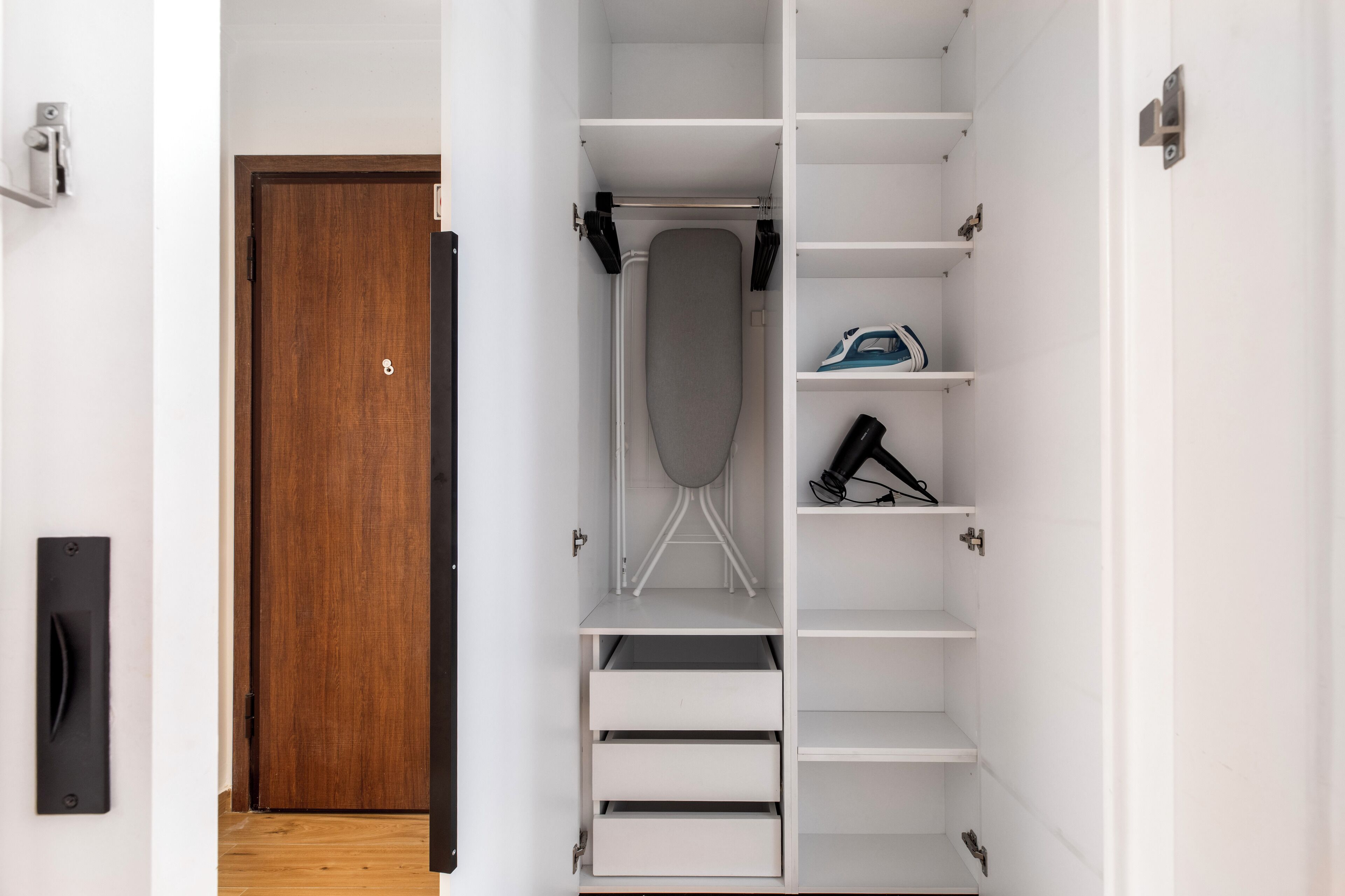 Een inloopkast met een houten deur, planken en lades.