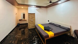 Une chambre d’hôtel de taille réduite, comprenant un lit, un petit bureau, un miroir et une armoire.