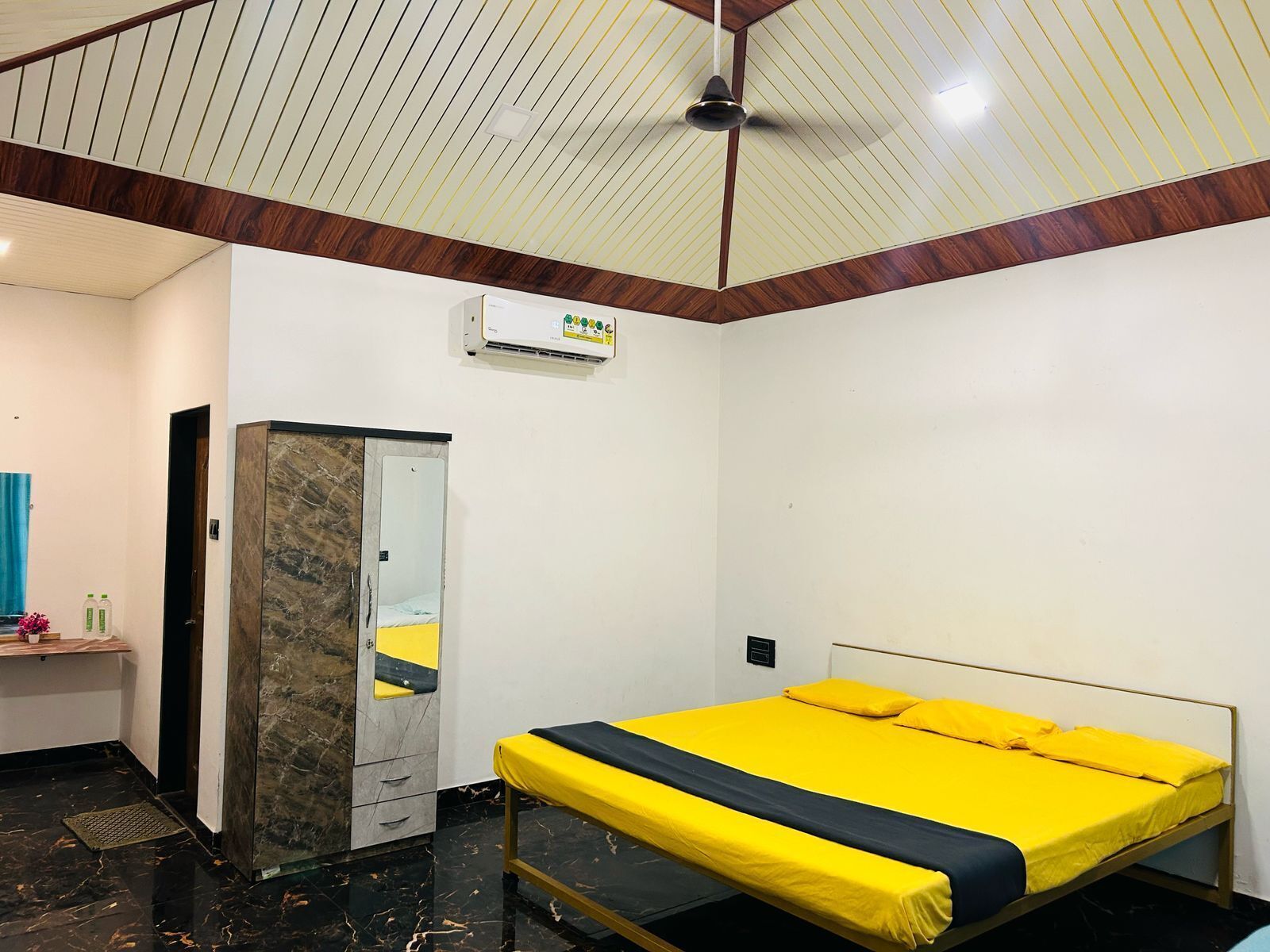 A bedroom with a bed, a wardrobe, a mirror, and an air conditioning unit.