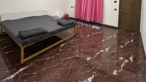 Une chambre à coucher avec un lit, un ventilateur de plafond, une porte et une fenêtre avec des rideaux.
