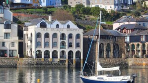 A coastal building named "The Packet Quays" with a sailboat docked nearby. - Tobys Quay (Falmouth)