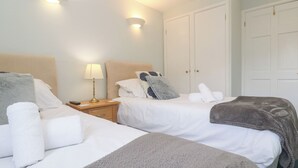 A hotel room with two beds, a nightstand with a lamp, and a wardrobe. - Tobys Quay (Falmouth)