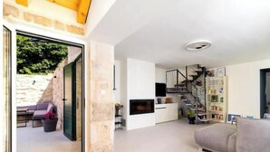 A modern living room with a fireplace, a staircase, and a bookshelf.
