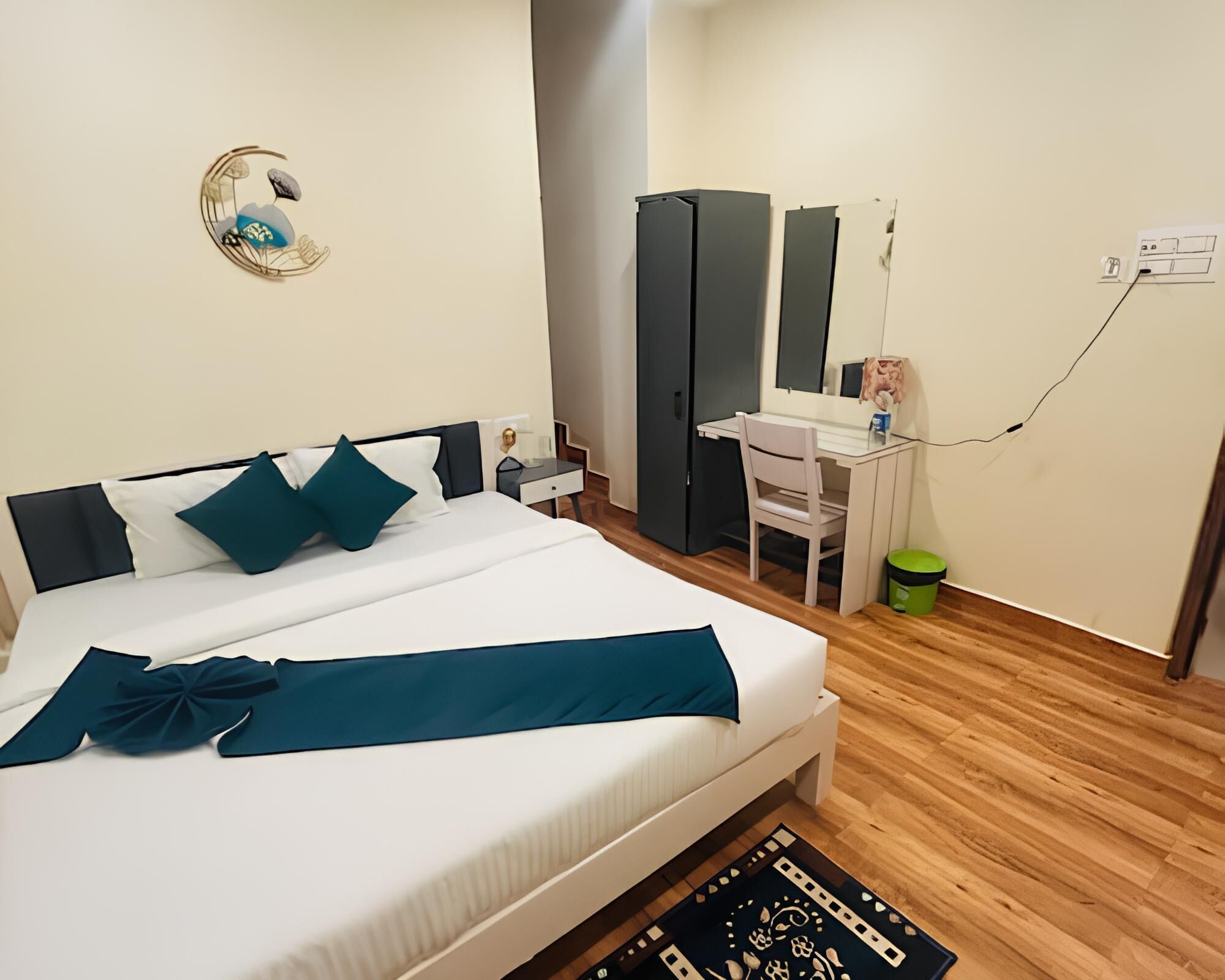 A neatly arranged bedroom with a bed, bedside table, dresser, and a desk with a chair.