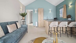 A modern living room with a sofa, a coffee table, and a kitchen area with a bar. - Kas Blou Blou with refreshing communal pool (Kralendijk)
