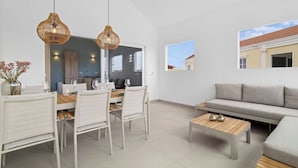 A modern living room with a dining area, a sofa, and a coffee table. - Kas Blou Blou with refreshing communal pool (Kralendijk)