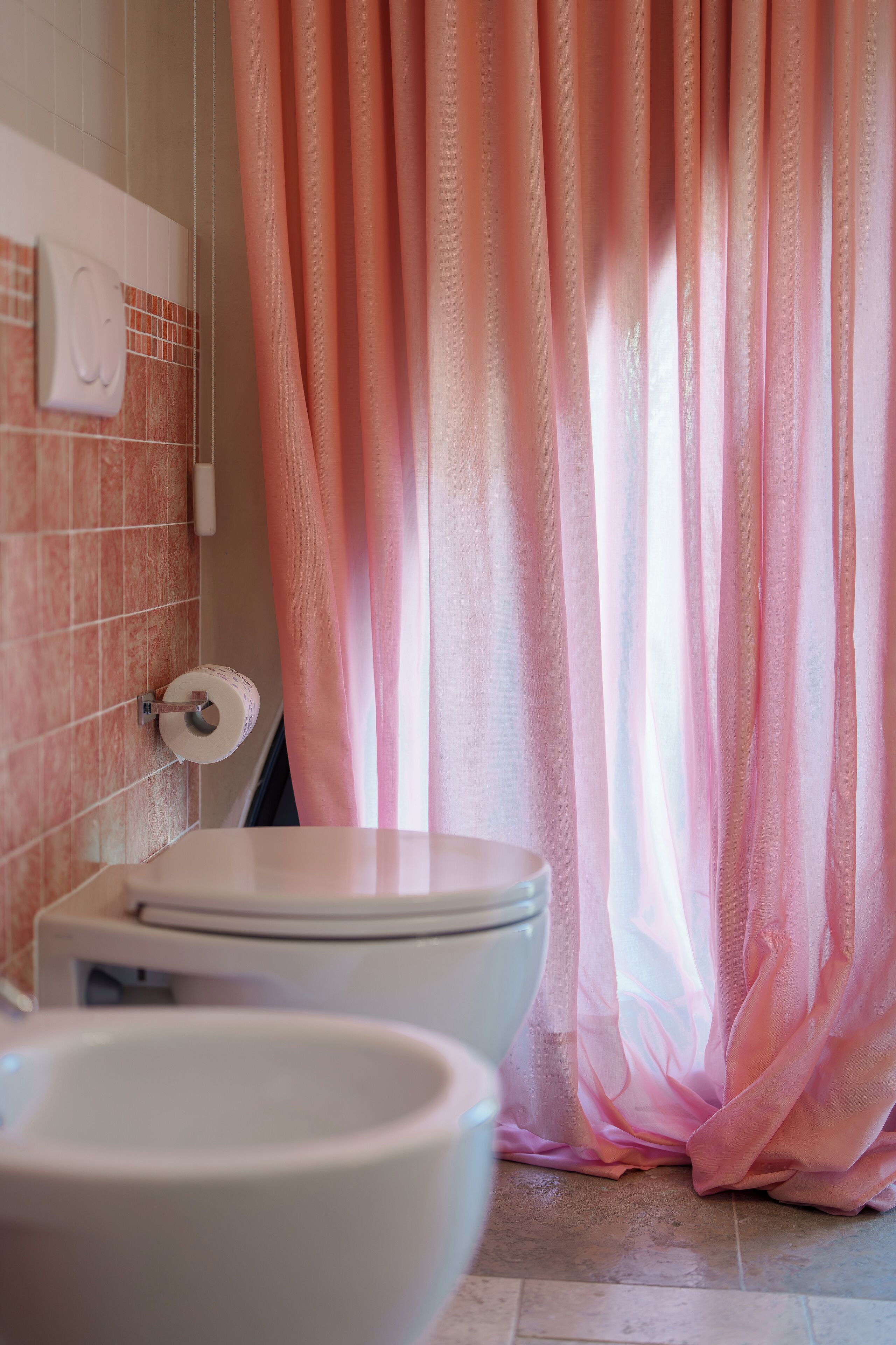 Un baño con inodoro, lavabo y cortina de ducha rosa.