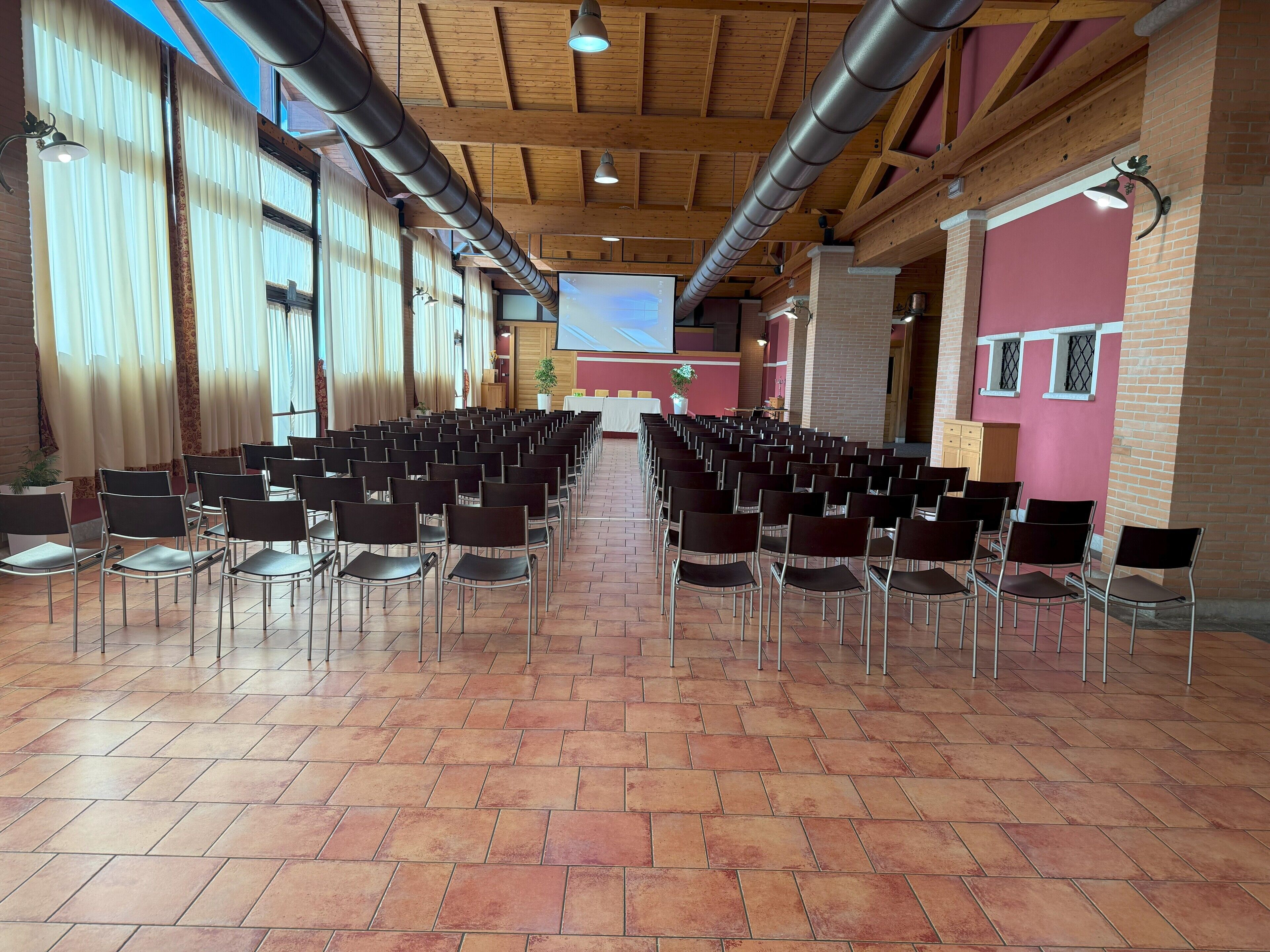 A conference room with rows of chairs, a stage, and a projector screen.