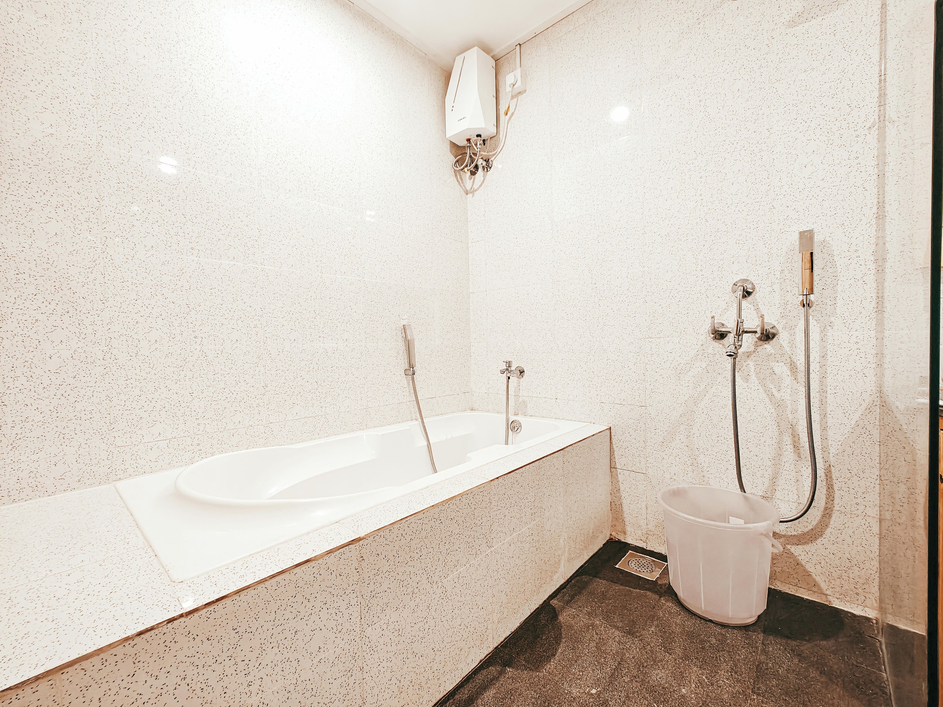 Un baño moderno con una bañera independiente, un cabezal de ducha y un calentador de pared.