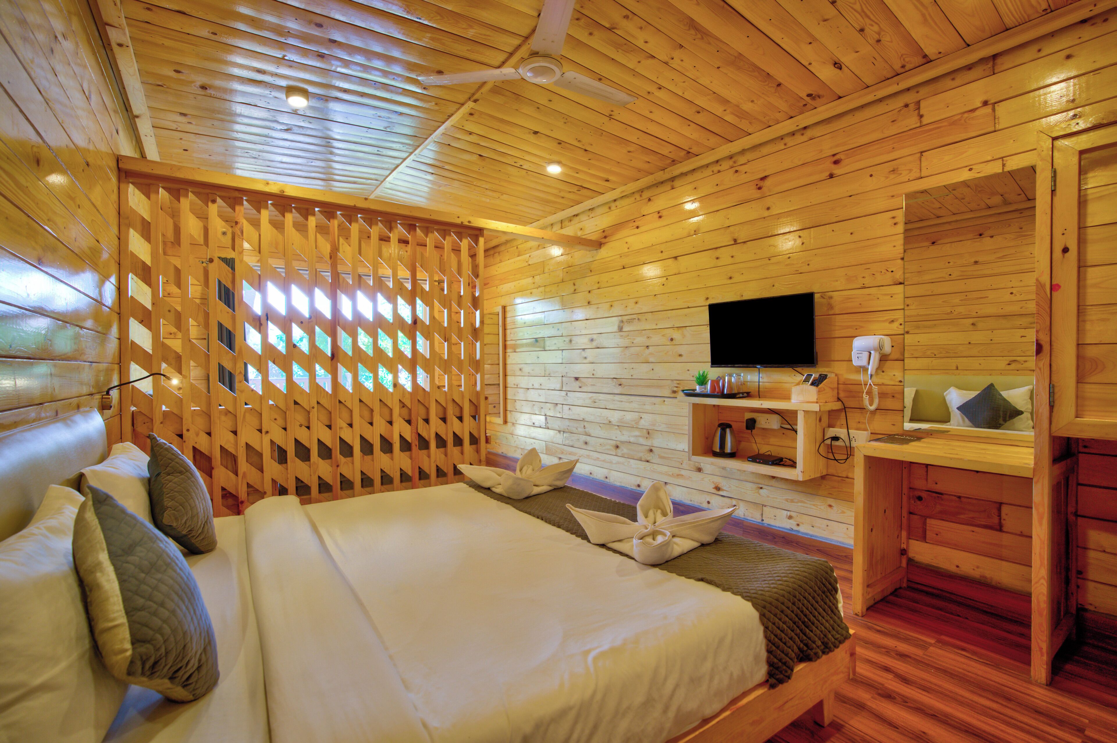 A wooden cabin-style room with a bed, a TV, and a desk.