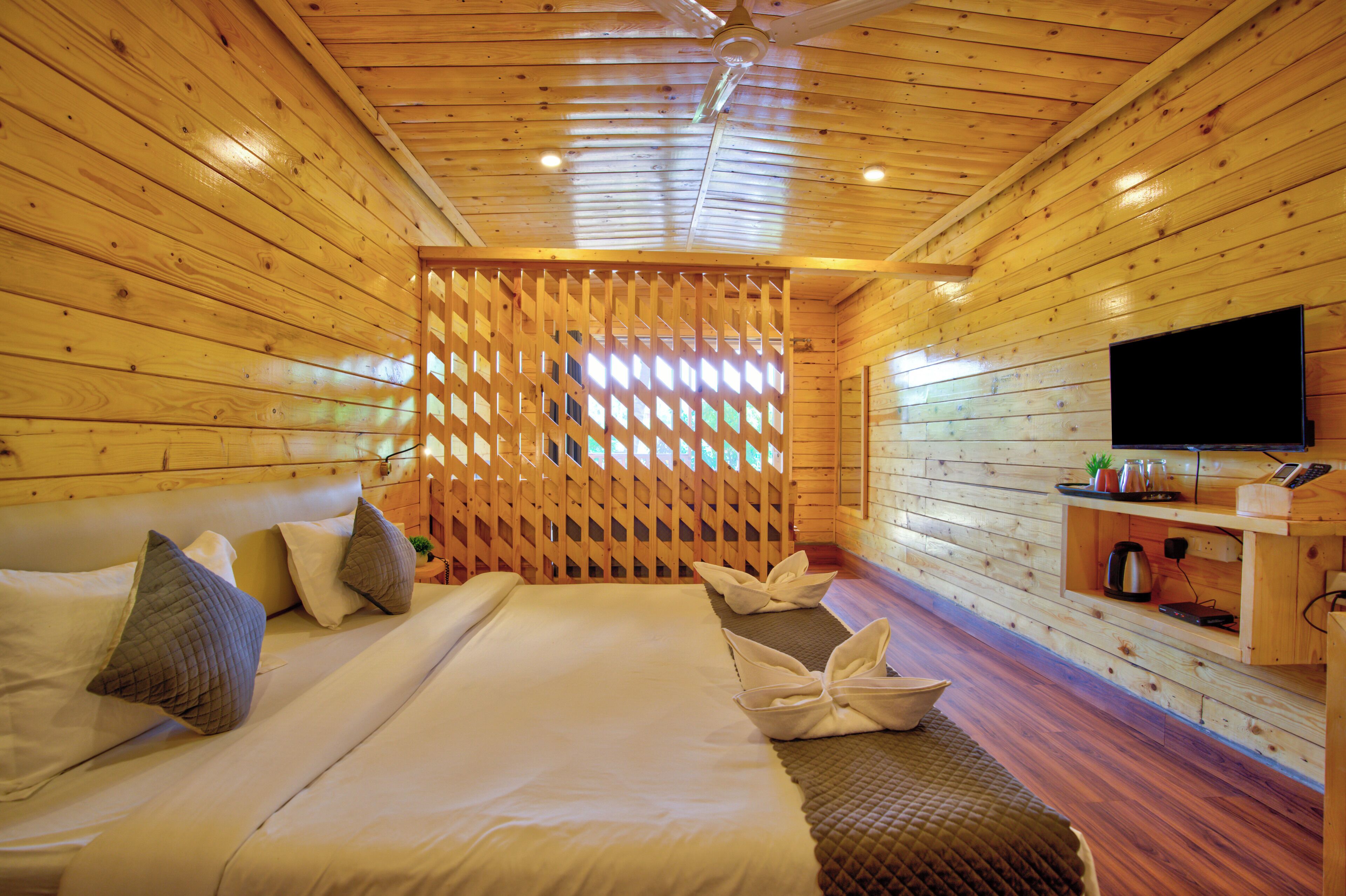 Habitación de cabaña de madera con cama, almohadas, un televisor y una repisa con objetos.