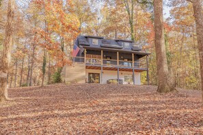 A two-story cabin with a balcony, surrounded by a forest with autumn foliage. - Creekside Cabin in Blue Ridge, GA (Epworth)