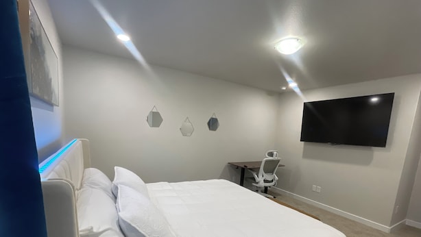 Un dormitorio con una cama, un escritorio y un televisor.