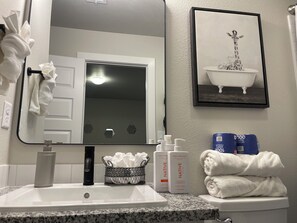 Ein Badezimmer mit Waschbecken, Spiegel und Toilettenartikeln.