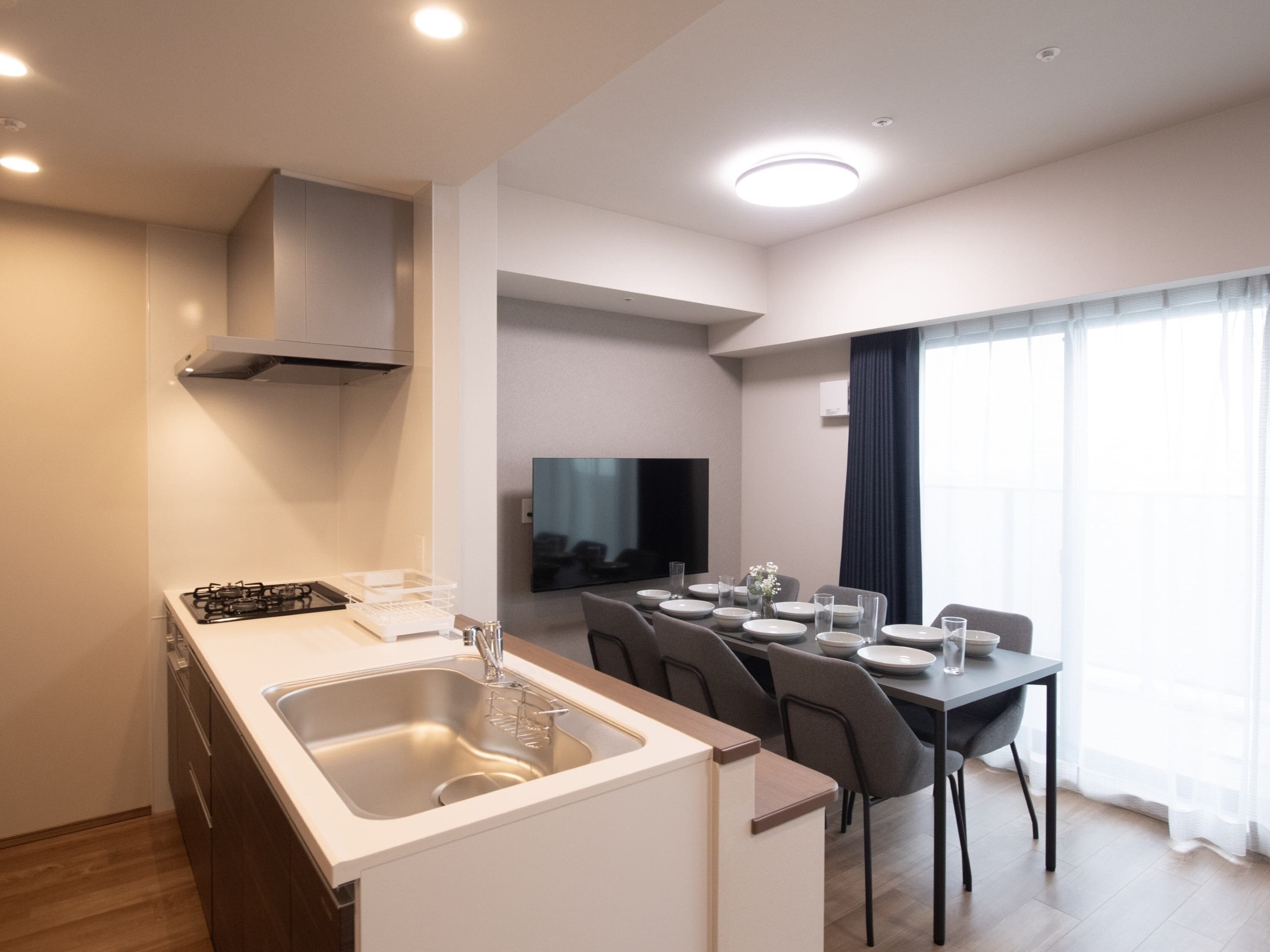 A modern kitchen with a built-in stove, sink, and a dining area with a table set for four.