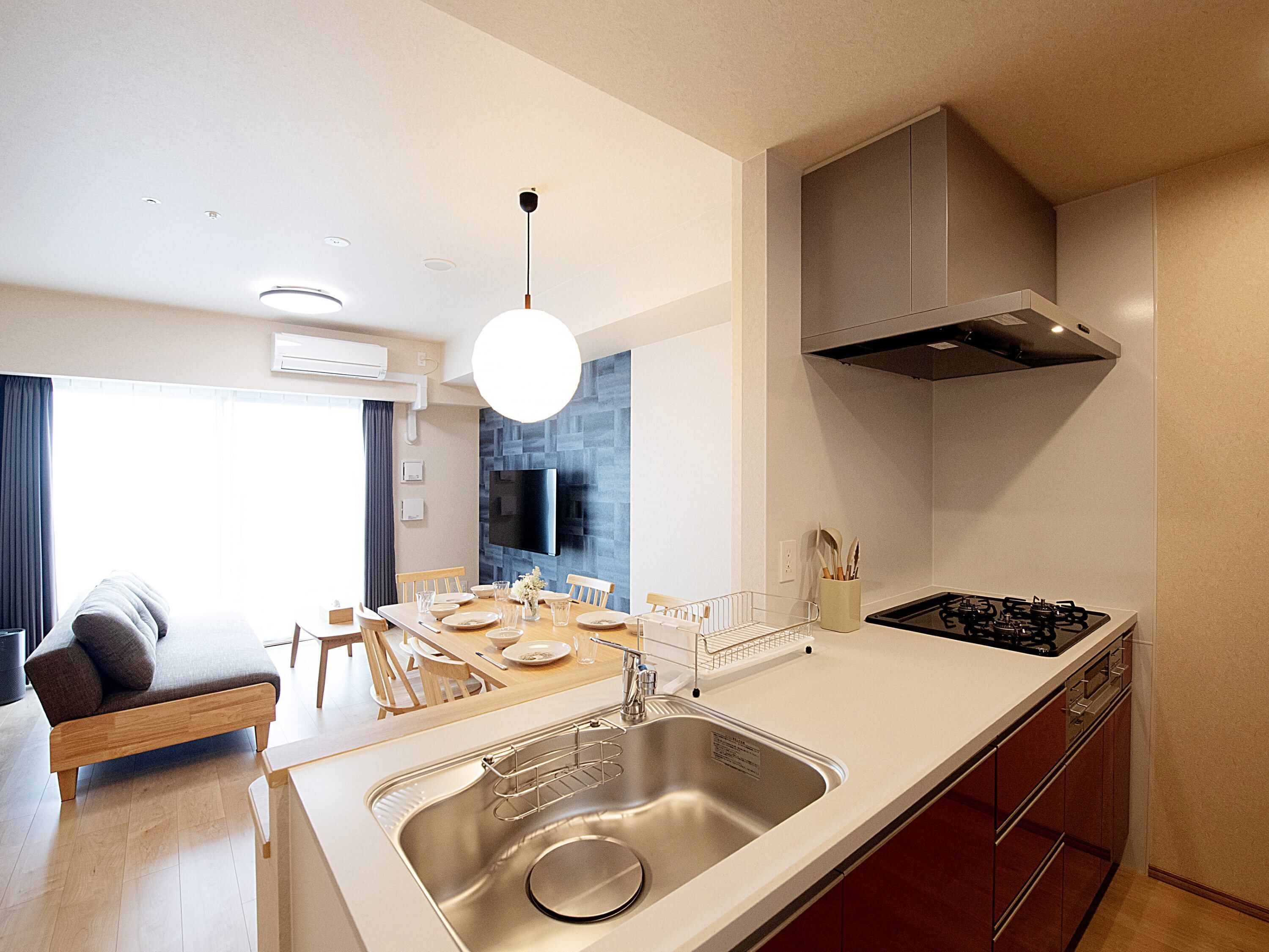 A modern kitchen with a stainless steel sink, a gas stove, and a dining area with a table and chairs.