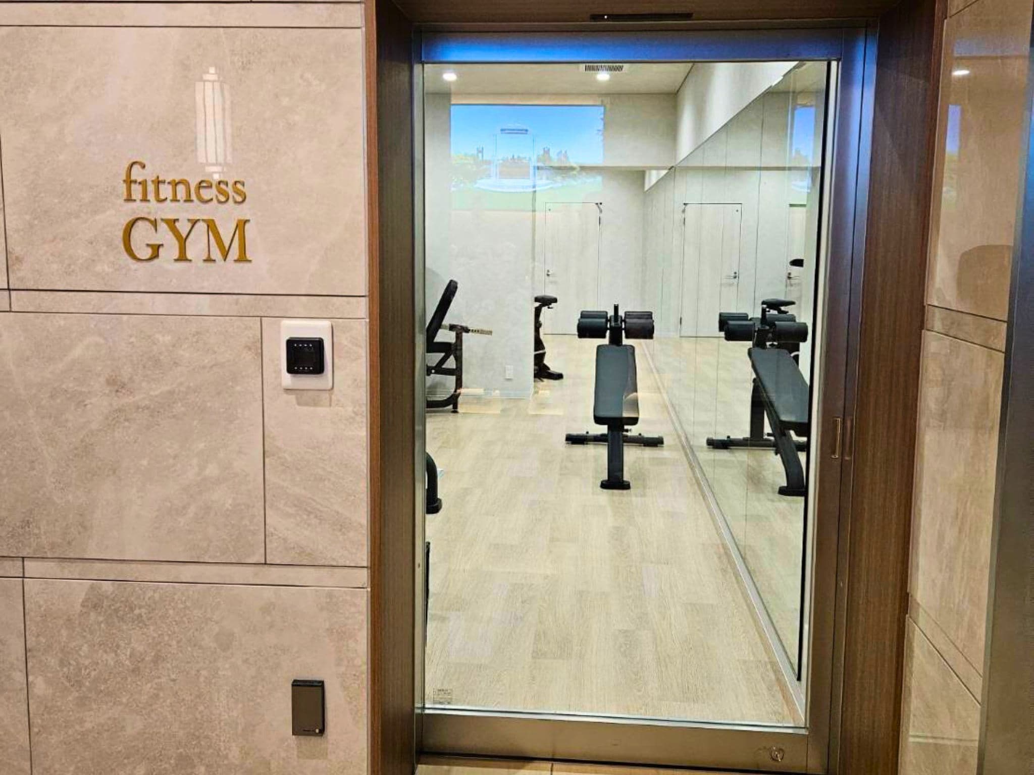 Une salle de sport équipée de matériel d’exercice, d’un miroir et d’une enseigne indiquant « salle de sport ».