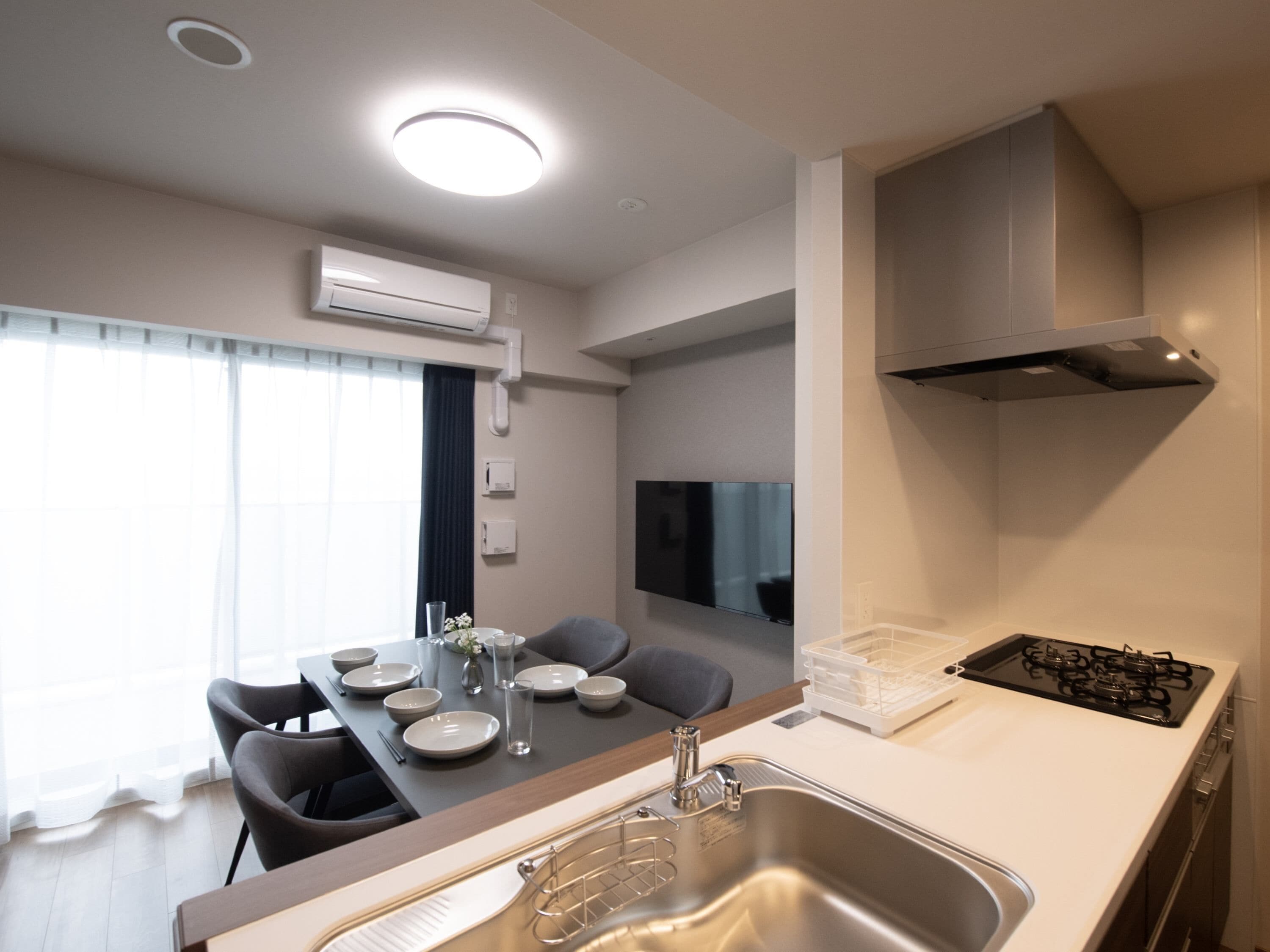 A modern kitchen with a dining area, stainless steel appliances, and a flat-screen TV.