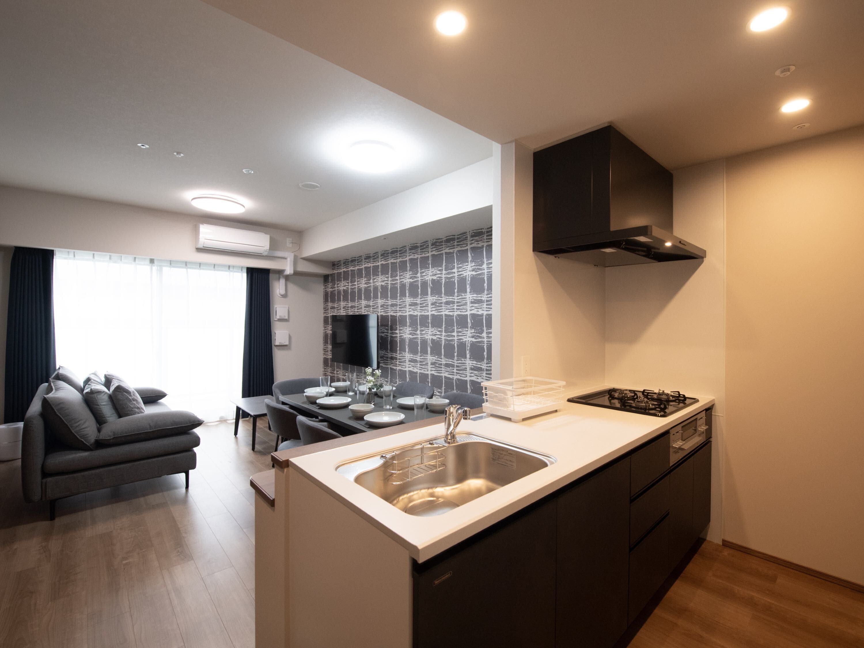 A modern kitchen with a central island, a dining area with a table and chairs, and a living area with a sofa.